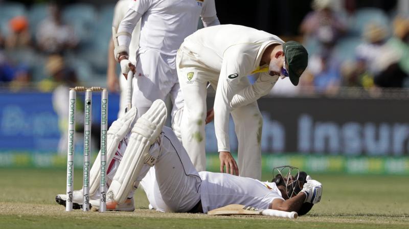 Australia's Nathan Lyon bends over to check on Sri Lanka's Dimuth Karunaratne after he was struck in the head by a delivery from Pat Cummins on day 2 of their cricket test match. (Photo: AP) Australia's Nathan Lyon bends over to check on Sri Lanka's Dimuth Karunaratne after he was struck in the head by a delivery from Pat Cummins on day 2 of their cricket test match. (Photo: AP)