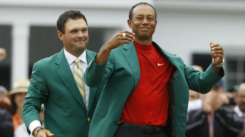 Patrick Reed helps Tiger Woods with his green jacket after Woods won the Masters golf tournament on April 14 last year in Augusta, Georgia. AP Photo