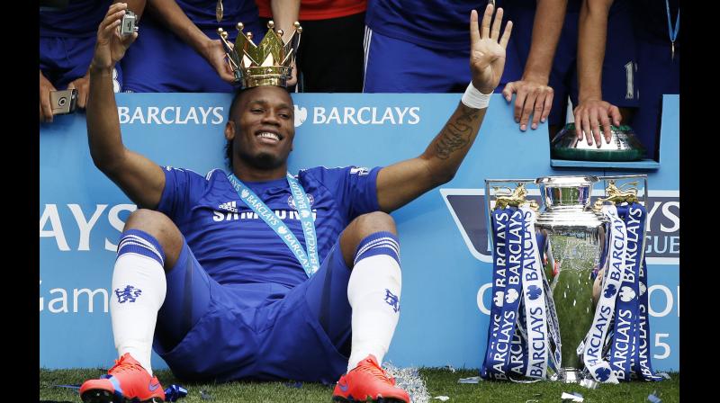 Chelseas Ivorian striker Didier Drogba wears the crown holding a camera as he poses with the Premier League trophy Chelsea has won in the 2014-2015 season. AFP Photo