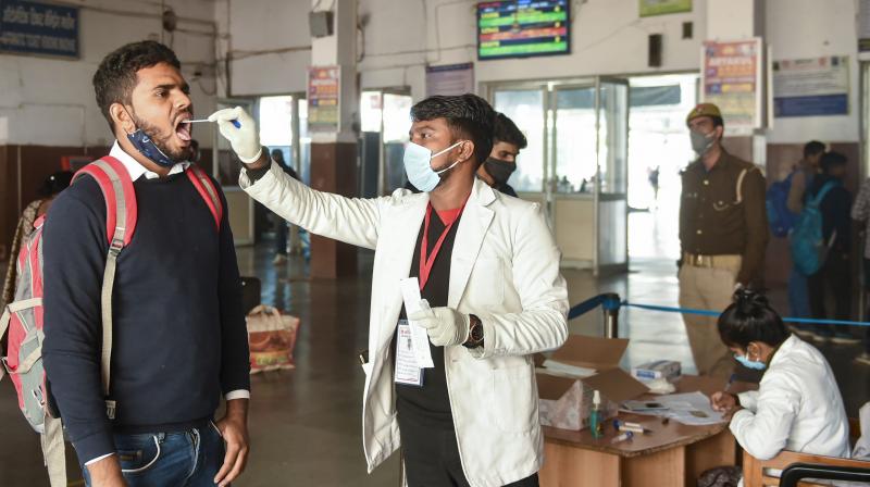 A medical worker collects swab sample of a passenger for Covid-19 test amid fear of spread of Omicron varaint, at Charbagh railway station in Lucknow. (PTI /Nand Kumar)