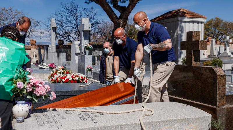 Mortuary employees wearing face masks burry the coffin of a COVID-19 coronavirus victim at Fuencarral cemetery in Madrid. AFP Photo