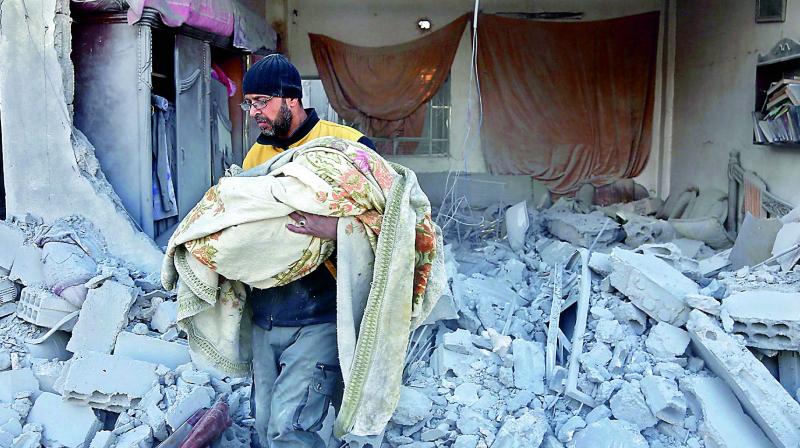 A member of the Syrian civil defence carries the body of a child out of a rubble in a house that was hit by a air strike in the rebel-held town of Jisreen. (Photo:AFP) A member of the Syrian civil defence carries the body of a child out of a rubble in a house that was hit by a air strike in the rebel-held town of Jisreen. (Photo:AFP)