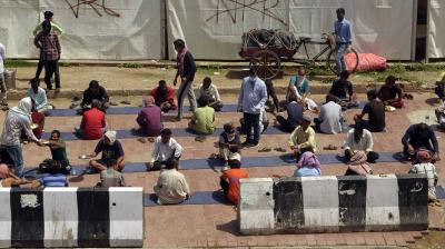 People thrown out of livelihoods sit down for a meal at a soup kitchen set up by the Delhi government at a temporary shelter in the Nizamuddin area. (DC Photo: Pritam Bandyopadhyay)