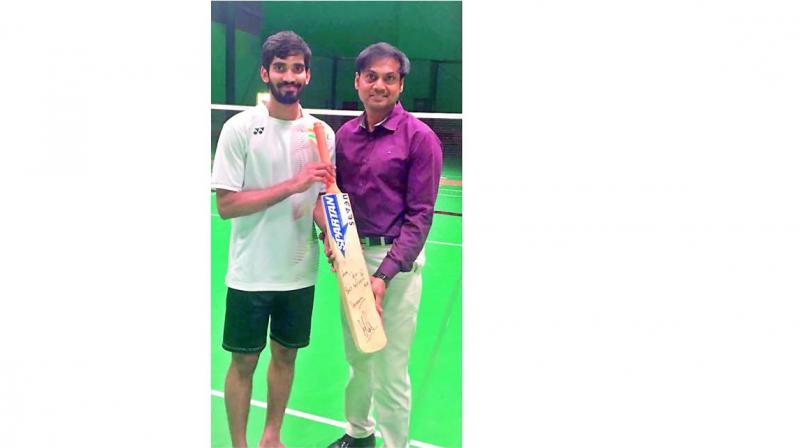 Indian shuttler Kidambi Srikanth (left) poses alongside chairman of national cricket selection committee MSK Prasad with the Mahendra Singh Dhoni-signed bat. Indian shuttler Kidambi Srikanth (left) poses alongside chairman of national cricket selection committee MSK Prasad with the Mahendra Singh Dhoni-signed bat.