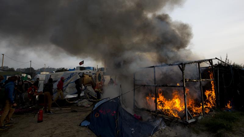 Firefighters work extinguishing burning tents in a makeshift migrant camp known as "the jungle" near Calais, northern France, on Wednesday. (Photo: AP) Firefighters work extinguishing burning tents in a makeshift migrant camp known as "the jungle" near Calais, northern France, on Wednesday. (Photo: AP)
