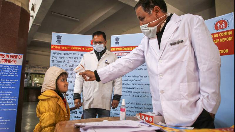 A doctor checks the temperature of a child passenger as part of precautionary measures against the new coronavirus, at a railway station in Jammu (PTI)