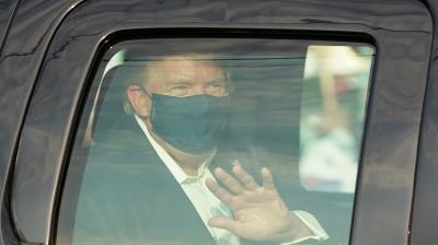 US President Trump waves from the back of a car in a motorcade outside of Walter Reed Medical Center in Bethesda, Maryland on October 4, 2020. (AFP)