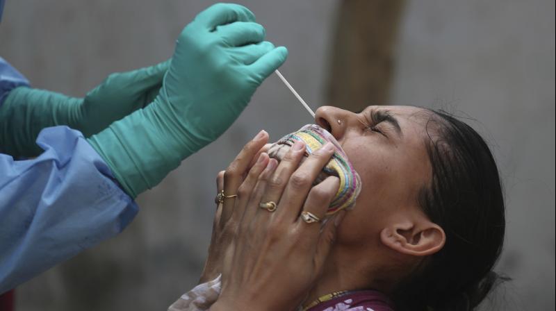 A woman reacts to a swab test being taken to check for Covid-19 infection in Ahmedabad on April 10, 2020. (AP) A woman reacts to a swab test being taken to check for Covid-19 infection in Ahmedabad on April 10, 2020. (AP)