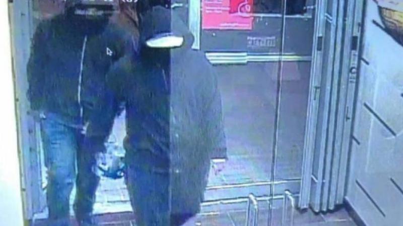 Police posted a photograph on Twitter showing two people with dark zip-up hoodies walking into an establishment with one of them appearing to be carrying an object. (Photo | Peel Regional Police Twitter) Police posted a photograph on Twitter showing two people with dark zip-up hoodies walking into an establishment with one of them appearing to be carrying an object. (Photo | Peel Regional Police Twitter)