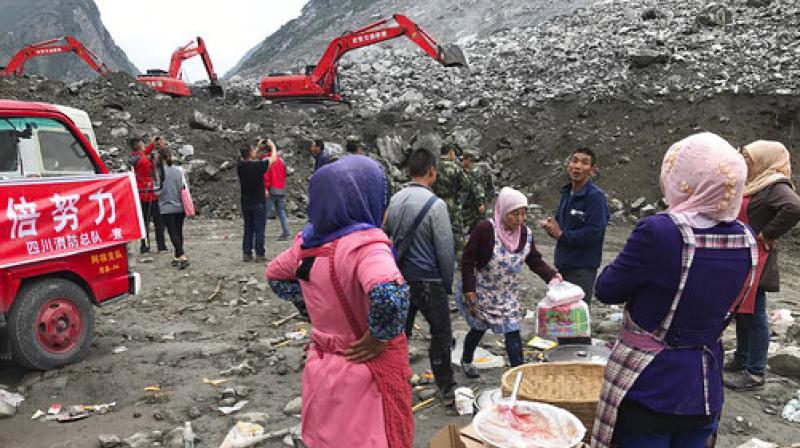Women watch as earthmoving equipment digs at the site of a landslide in Xinmo village in Maoxian County in southwestern China's Sichuan Province, Sunday. (Photo: AP) Women watch as earthmoving equipment digs at the site of a landslide in Xinmo village in Maoxian County in southwestern China's Sichuan Province, Sunday. (Photo: AP)