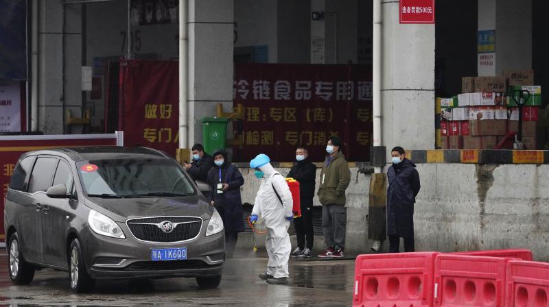 A worker in protective overall disinfects a vehicle from the World Health Organization convoy while they were visiting the Baishazhou wholesale market on the third day of field visit in Wuhan in central Chinas Hubei province on Sunday, Jan. 31, 2021. (AP)