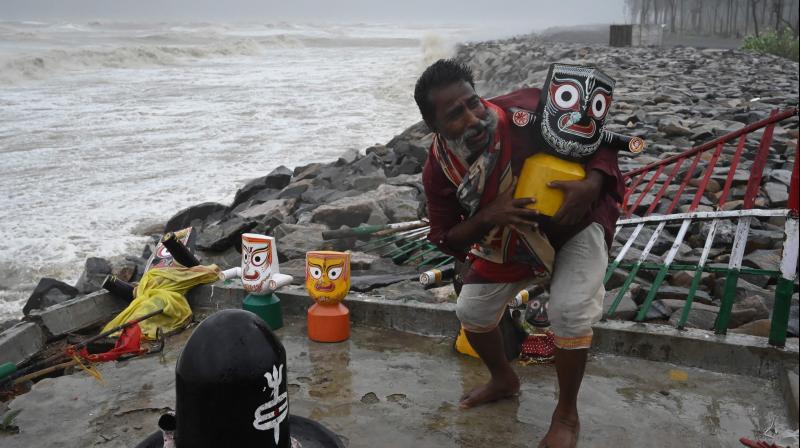 A priest removes an idol of Lord Jagannath from a seafront temple to a safer place while strong winds batter Balasore district in Odisha as Cyclone Yaas barrels towards Indias eastern coast in the Bay of Bengal. (Photo: AFP)