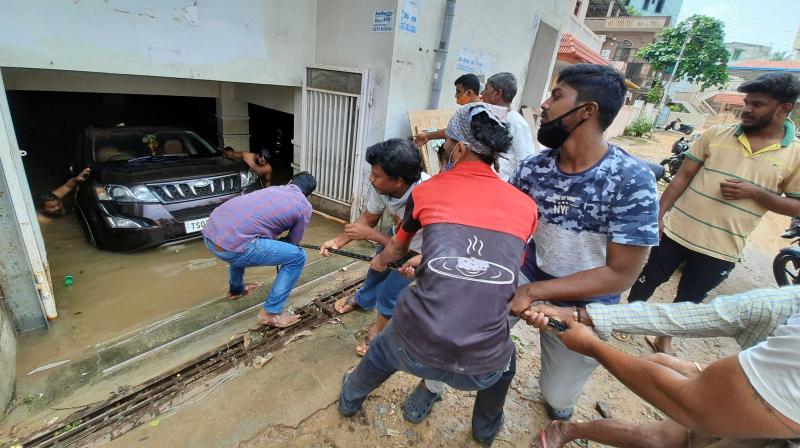 Local residents in Dilsukhnagar pull out a car from a cellar using ropes.  P Surendra pic