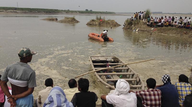 Rescuers search in the Yamuna River as villagers gather after a country boat, seen in foreground, capsized near Baghpat town in Uttar Pradesh on Thursday. (Photo: AP) Rescuers search in the Yamuna River as villagers gather after a country boat, seen in foreground, capsized near Baghpat town in Uttar Pradesh on Thursday. (Photo: AP)