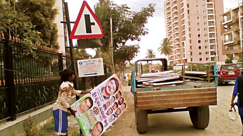 A BBMP worker removes flexes at a traffic junction, in Bengaluru A BBMP worker removes flexes at a traffic junction, in Bengaluru