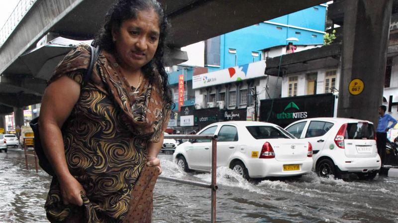 A woman wades through the water logged M G Road after heavy rains in Kochi. (Photo: PTI) A woman wades through the water logged M G Road after heavy rains in Kochi. (Photo: PTI)