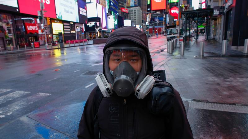 A man wears a face mask while he visits Times Square as rain falls in New York citu. AFP Photo