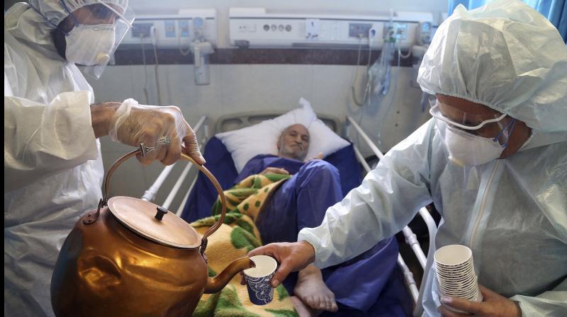 Paramedics treat a patient infected with the new coronavirus, at a hospital in Tehran, Iran,