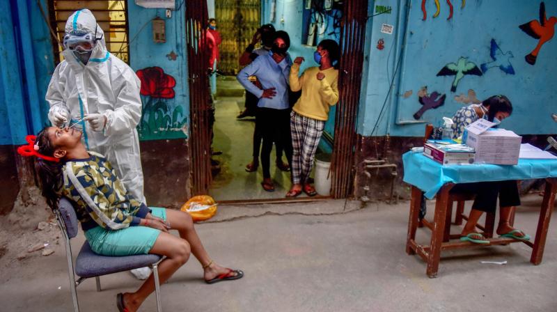 A health worker wearing PPE kit collects sample from a girl for COVID-19 test, at a Childrens Home in New Delhi, Saturday, Nov. 21, 2020. (PTI)