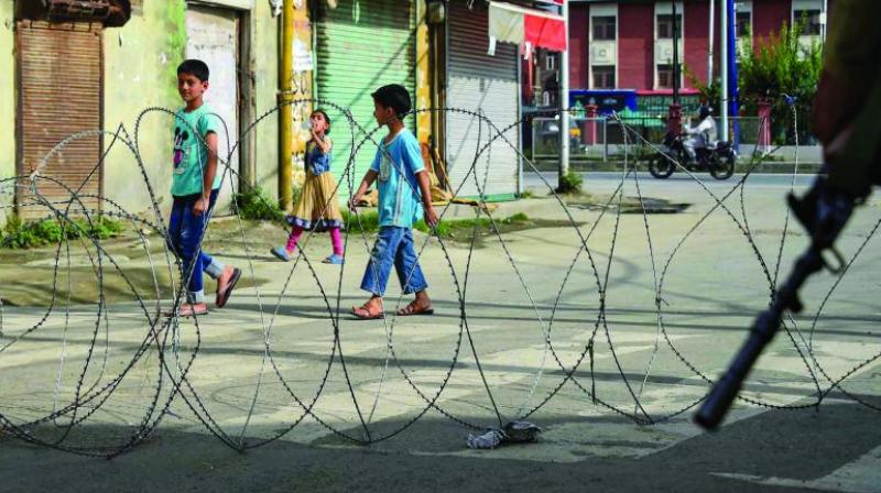 Children walk past concertina wire during restrictions following the abrogation of the provisions of Article 370 in Srinagar on Friday. (Photo: PTI) Children walk past concertina wire during restrictions following the abrogation of the provisions of Article 370 in Srinagar on Friday. (Photo: PTI)