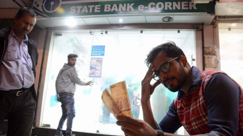 A man looks at his old Rs 500 notes outside a bank. (Photo: PTI) A man looks at his old Rs 500 notes outside a bank. (Photo: PTI)