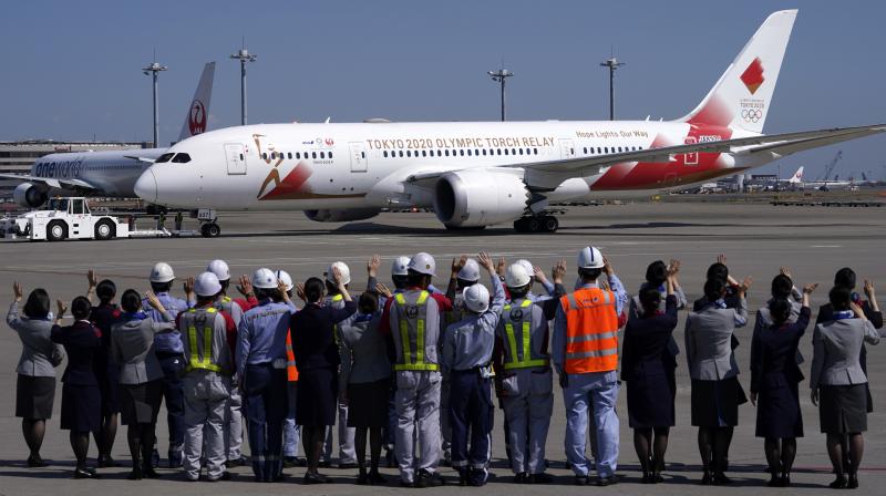 ground crews of Japanese airlines wave to the special \Tokyo 2020 Go\ aircraft that will transport the Olympic Flame to Japan after the Torch Handover Ceremony in Greece, departs at Haneda International Airport in Tokyo. The Olympic flame from Greece is set to arrive in Japan even as the opening of the the Tokyo Games in four months is in doubt with more voices suggesting the games should to be postponed or canceled because of the worldwide virus pandemic. (AP