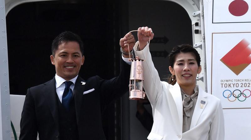 Japanese three-time Olympic Judo gold medallist Tadahiro Nomura (L) and three-time Olympic wrestling gold medallist Saori Yoshida display the flame as they step out of the special aircraft that brought 2020 Tokyo Olympic flame at the Japan Air Self-Defense Force Matsushima Base in Higashimatsushima, Miyagi prefecture, on Friday. AFP Photo