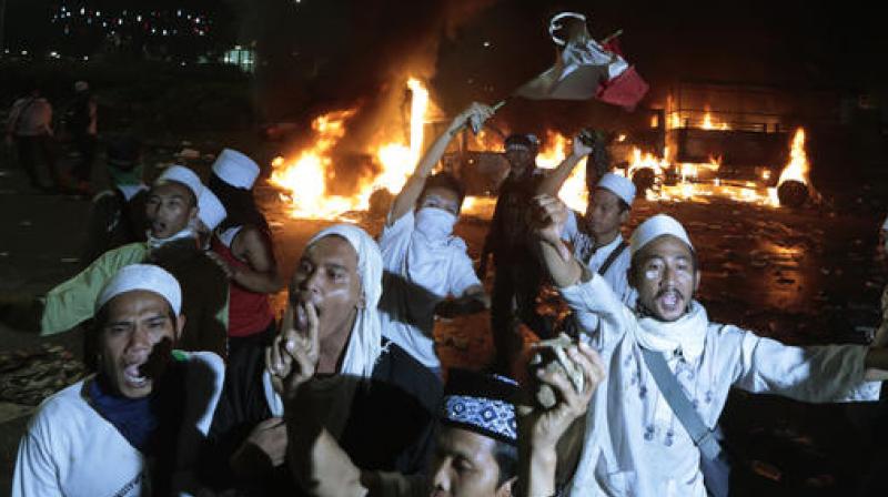 Muslim protesters chant slogans near burning police trucks during a clash with the police outside the presidential palace in Jakarta. (Photo: AP) Muslim protesters chant slogans near burning police trucks during a clash with the police outside the presidential palace in Jakarta. (Photo: AP)