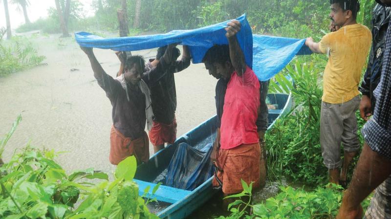 People shielding the dead body of Sathyan, 45, from rain near Kuniyil Kadav bridge, part of Korapuzha who was trapped in floods on Thursday. (Photo: Venugopal) People shielding the dead body of Sathyan, 45, from rain near Kuniyil Kadav bridge, part of Korapuzha who was trapped in floods on Thursday. (Photo: Venugopal)