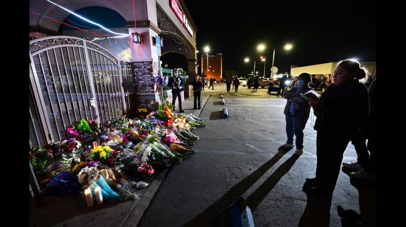 A woman reads passages from a bile in front of a makeshift memorial for victims of a mass shooting outside the Star Dance Studio in Monterey Park, California on January 23, 2023. - The 72-year-old Asian immigrant who killed 11 people on January 21, 2023, before shooting himself as police moved in on him was once a regular at the California dance club where a tragic gun massacre unfolded. (Photo: AFP)