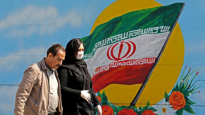 An Iranian woman wearing a mask walks past a mural displaying her national flag in Tehran. AFP Photo An Iranian woman wearing a mask walks past a mural displaying her national flag in Tehran. AFP Photo