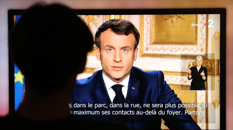 French President Emmanuel Macron is seen on a television screen as he speaks during a televised address to the nation on the outbreak of COVID-19, caused by the novel coronavirus in Paris. AFP Photo