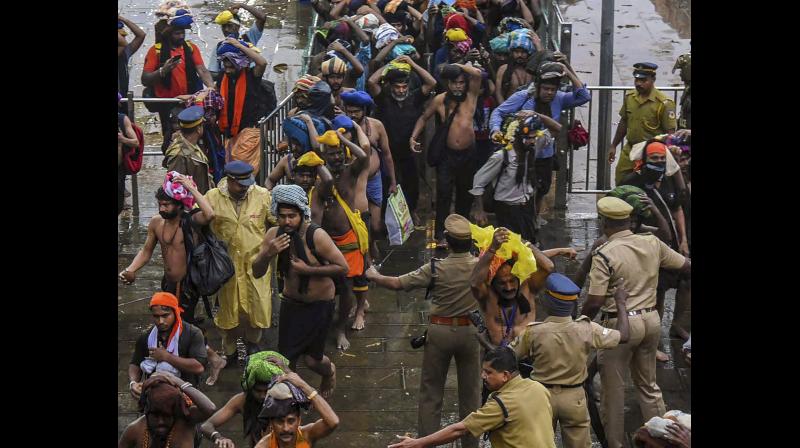 Devotees enter the Sabarimala temple as it opens amid tight security on Friday. (Photo: PTI) Devotees enter the Sabarimala temple as it opens amid tight security on Friday. (Photo: PTI)