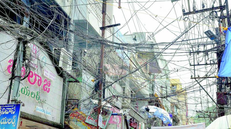 A mesh of power and other cables entangled at One Town Sivalayam Steet in Vijayawada. This is a common phenomenon in many poarts of the city. (Photo: DC) A mesh of power and other cables entangled at One Town Sivalayam Steet in Vijayawada. This is a common phenomenon in many poarts of the city. (Photo: DC)