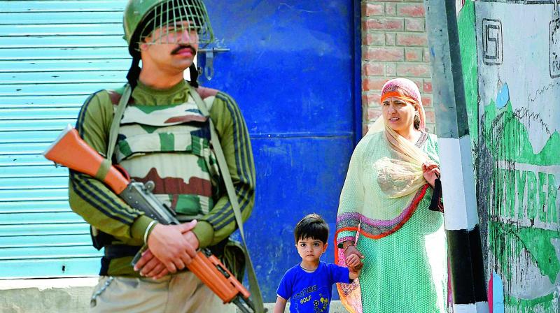 A woman and her son look on as a security guard stands at a block road during curfew imposed on the first death anniversary of Hizbul Mujahideen commander Burhan Wani, in Srinagar, on Saturday. (Photo: PTI) A woman and her son look on as a security guard stands at a block road during curfew imposed on the first death anniversary of Hizbul Mujahideen commander Burhan Wani, in Srinagar, on Saturday. (Photo: PTI)