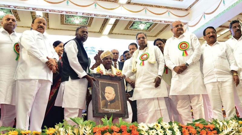 Chief Minister Siddaramaiah honours veteran Congress leader Mallikarjun Kharge with Devaraj Urs Award at a function to mark the 102nd birth anniversary of the former CM in Bengaluru on Sunday. (Photo: DC) Chief Minister Siddaramaiah honours veteran Congress leader Mallikarjun Kharge with Devaraj Urs Award at a function to mark the 102nd birth anniversary of the former CM in Bengaluru on Sunday. (Photo: DC)
