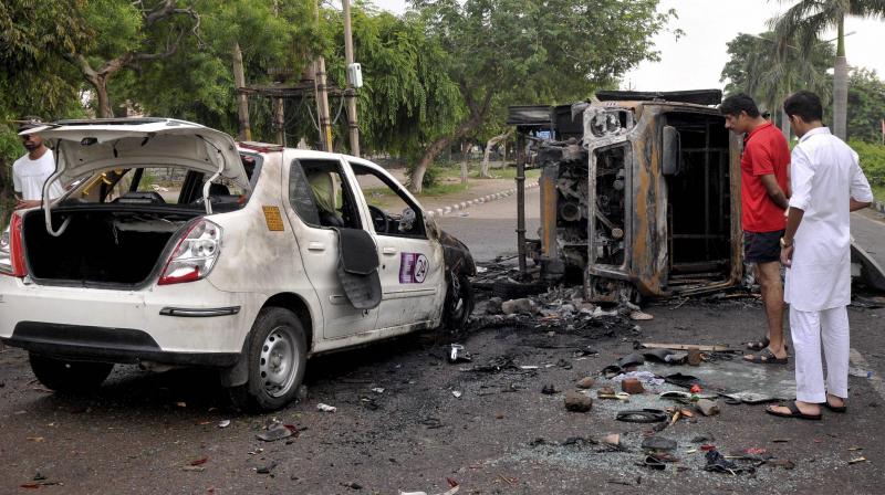 Charred vehicles lying on a road which were torched during violence triggered by the conviction of Dera Sacha Sauda head Gurmeet Ram Rahim Singh in a rape case. (Photo: PTI) Charred vehicles lying on a road which were torched during violence triggered by the conviction of Dera Sacha Sauda head Gurmeet Ram Rahim Singh in a rape case. (Photo: PTI)