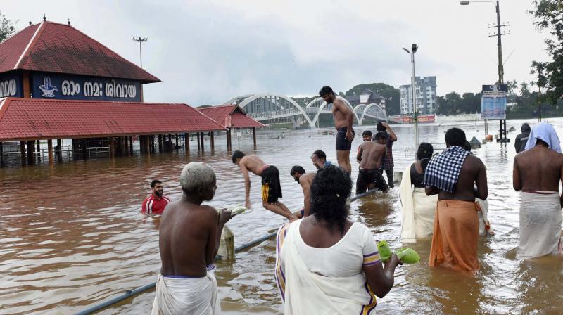 Devotees near the flooded Aluva Siva Temple in Kochi on Monday, as heavy rain continues to lash different parts of the Kerala state. (Photo: PTI) Devotees near the flooded Aluva Siva Temple in Kochi on Monday, as heavy rain continues to lash different parts of the Kerala state. (Photo: PTI)