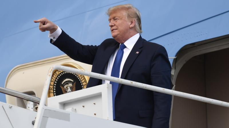 President Donald Trump points to the crowd as he stands with his son Barron Trump, right, on the top of the steps of Air Force One at Palm Beach International Airport in West Palm Beach, Flordia. AP photo