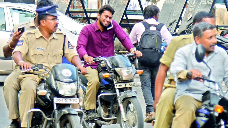 Cops return from a briefing on security arrangements for the Opposition-sponsored ‘Chalo Dharna Chowk’ rally without wearing helmets and one of them even talking on the phone while riding his bike. (Photo: S. Surender Reddy) Cops return from a briefing on security arrangements for the Opposition-sponsored ‘Chalo Dharna Chowk’ rally without wearing helmets and one of them even talking on the phone while riding his bike. (Photo: S. Surender Reddy)