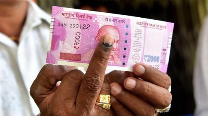 A man displays the currency notes and indelible ink after withdrawing the amount at the State Bank in Bengaluru. (Photo: PTI) A man displays the currency notes and indelible ink after withdrawing the amount at the State Bank in Bengaluru. (Photo: PTI)