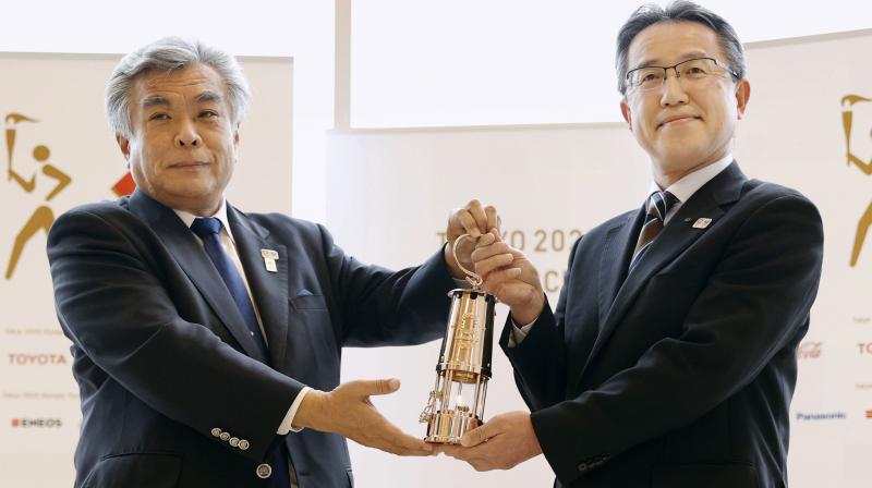Makoto Noji (R) Fukushima prefectural official in charge of sports and culture and Tokyo 2020 COO Yukihiko Nunomura, left, hold a lantern with the Olympic flame inside, during an official ¢â‚¬Åhandover ceremony¢â‚¬Â at the J-Village National Training Center, Fukushima Prefecture, Japan, Wednesday, April 1, 2020. The Olympic flame will be on display until the end of April in Japans northeastern prefecture of Fukushima.(Kyodo News via AP)