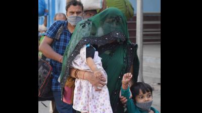 A migrant with her children steps out of Prayagraj railway station after arriving from Ahmedabad via special train. (PTI)
