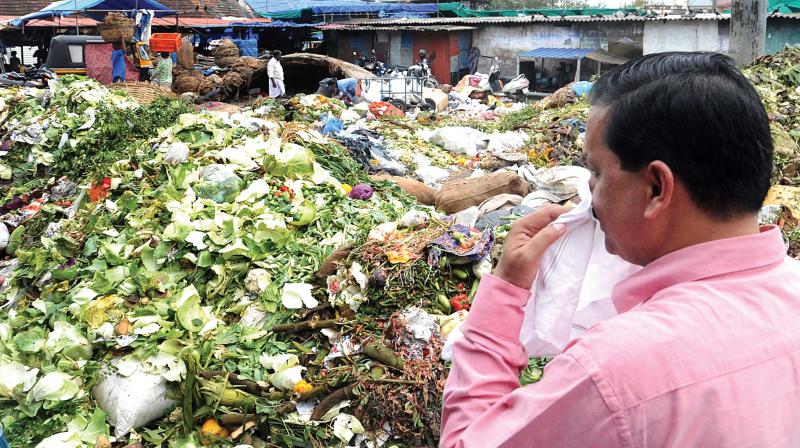 Sub-judge A M Basheer can't resist thumbing his nose at stench emanating from the waste at Ernakulam Market on Tuesday. ARUN CHANDRABOSE Sub-judge A M Basheer can't resist thumbing his nose at stench emanating from the waste at Ernakulam Market on Tuesday. ARUN CHANDRABOSE