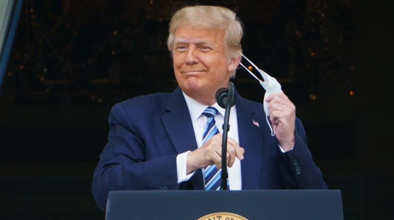 US President Donald Trump takes his mask off before speaking from the South Portico of the White House in Washington, DC during a rally on October 10, 2020. - Trump spoke publicly for the first time since testing positive for Covid-19, as he prepares a rapid return to the campaign trail just three weeks before the election. (AFP)