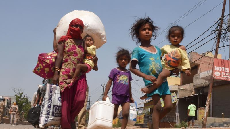 Migrant workers wait in a queue while being lodged at a camp by the Uttar Pradesh government, during ongoing COVID-19 lockdown, at Dadri. PTI Photo