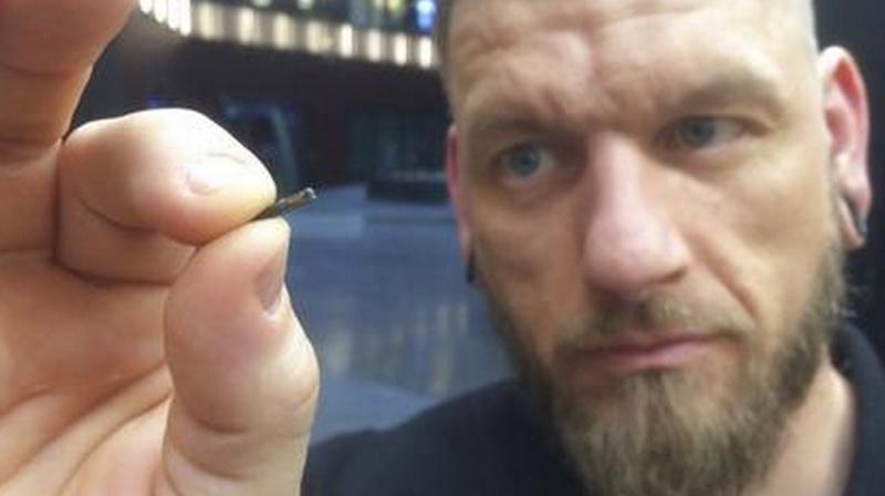Self-described “body hacker” Jowan Osterlund from Biohax Sweden, holds a small microchip implant, similar to those implanted into workers at the Epicenter digital innovation business centre during a party at the co-working space in central Stockholm, Tuesday March 14, 2017. Microchips are being implanted into volunteers to help them open doors and operate office equipment, and its become so popular that members of the Epicentre cyborg club hold regular parties for those with the tiny chips embedded in their hands. (AP Photo/James Brooks) Self-described “body hacker” Jowan Osterlund from Biohax Sweden, holds a small microchip implant, similar to those implanted into workers at the Epicenter digital innovation business centre during a party at the co-working space in central Stockholm, Tuesday March 14, 2017. Microchips are being implanted into volunteers to help them open doors and operate office equipment, and its become so popular that members of the Epicentre cyborg club hold regular parties for those with the tiny chips embedded in their hands. (AP Photo/James Brooks)