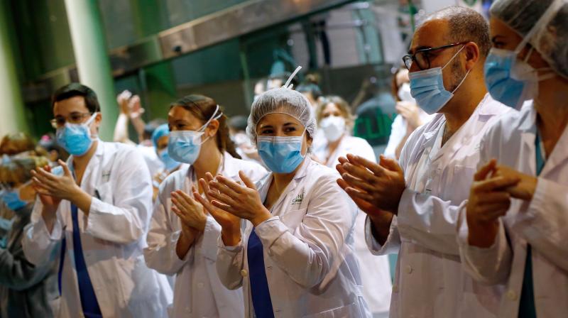 Healthcare workers dealing with the new coronavirus crisis in Spain applaud in return as they are cheered on by people outside \El Clinic\ University Hospital in Barcelona. AFP Photo