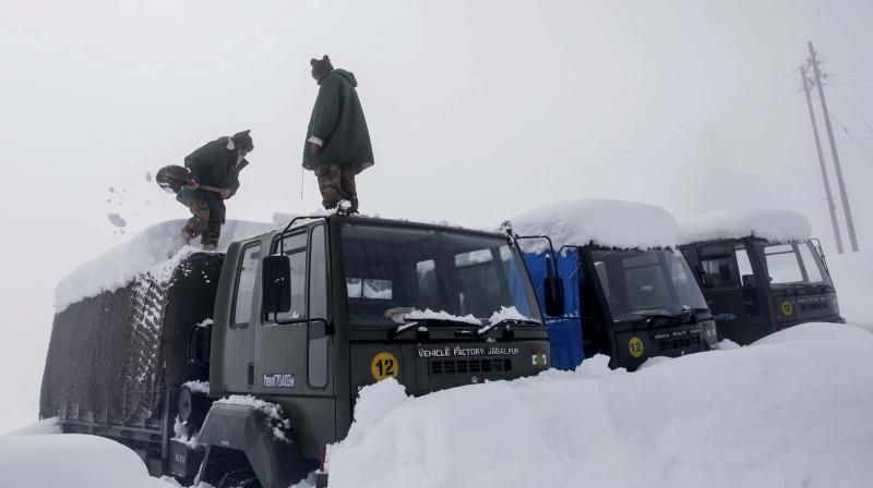 Indian Army soldiers clear snow from their stranded vehicles near a base camp in Gulmarg. (Photo: PTI) Indian Army soldiers clear snow from their stranded vehicles near a base camp in Gulmarg. (Photo: PTI)