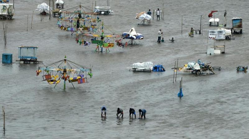 People walk through a flooded area of Marina Beach on the Bay of Bengal coast after heavy rains lashed Chennai for the eighth day. (Photo: AFP) People walk through a flooded area of Marina Beach on the Bay of Bengal coast after heavy rains lashed Chennai for the eighth day. (Photo: AFP)